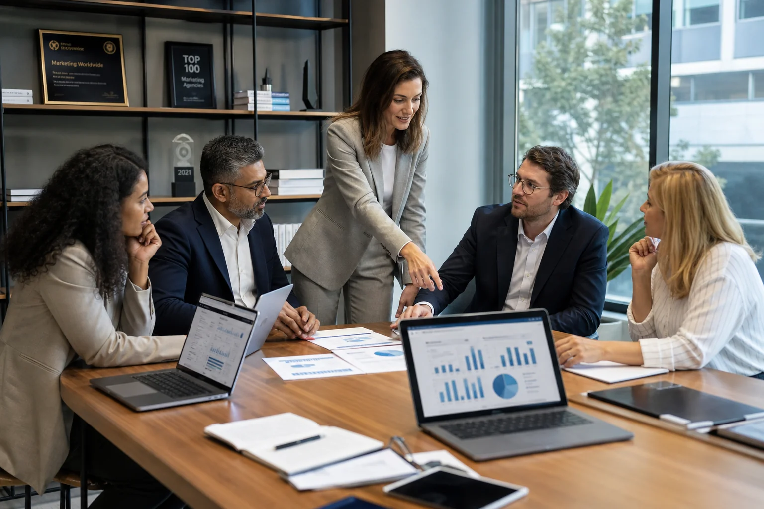 Diverse professionals collaborate in a bright, modern office, discussing reports at a large conference table, showcasing team