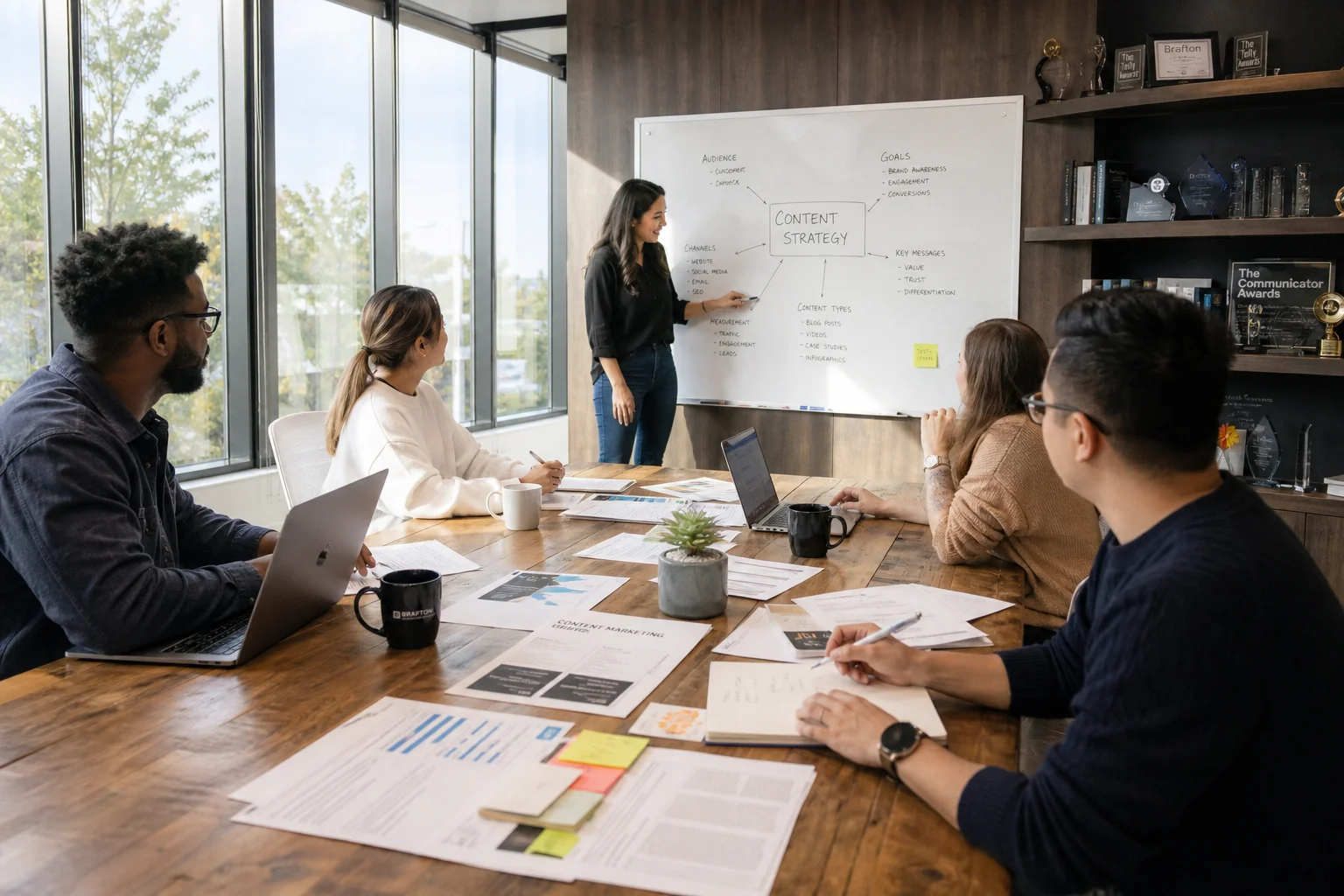 A diverse team of content marketers collaborates at a large table, brainstorming ideas in a bright, professional office setti